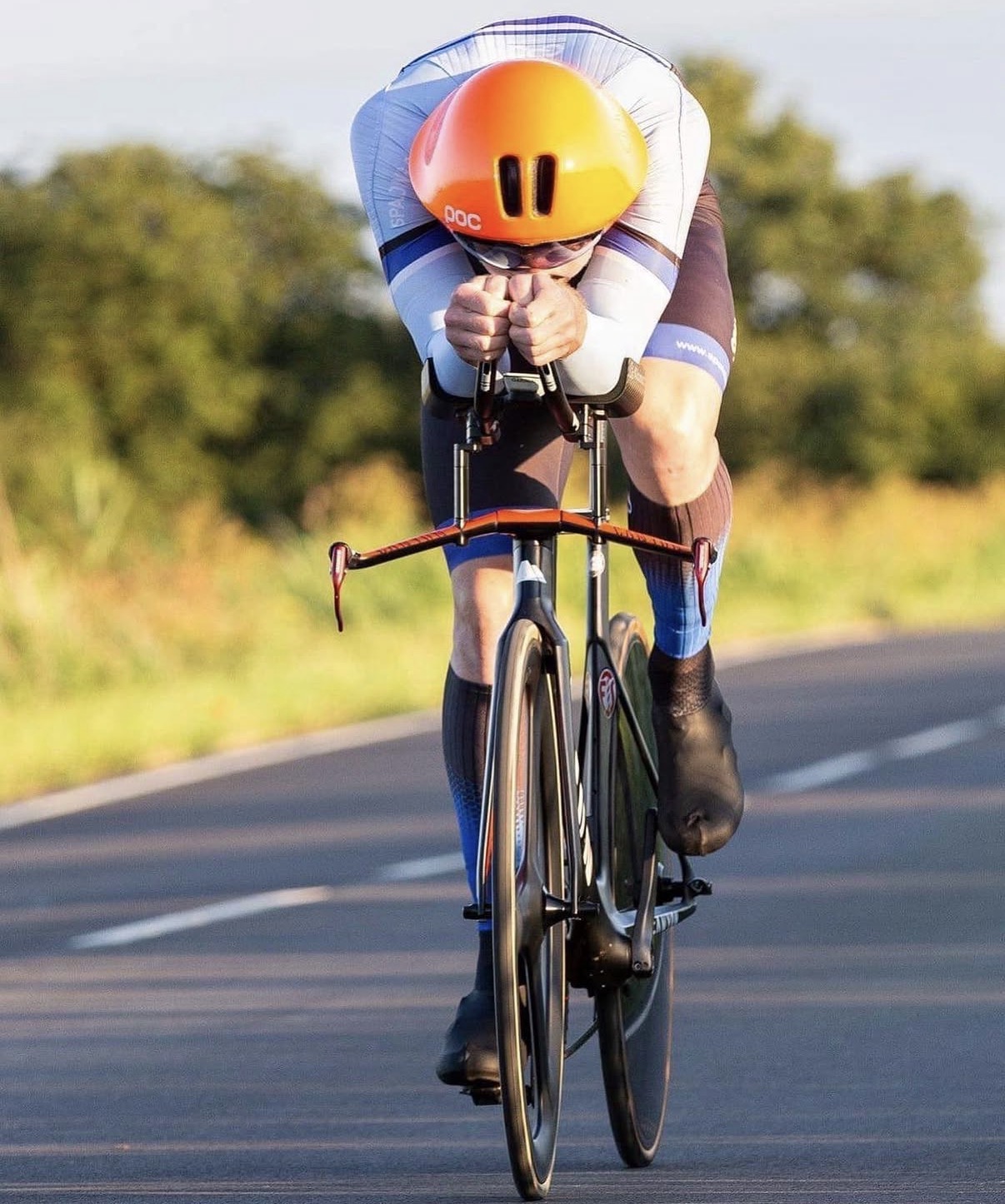 Time trial rider with orange helmet in aerodynamic position